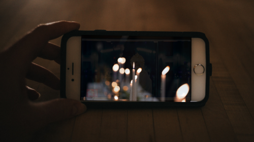 hand holding smartphone with candles on screen