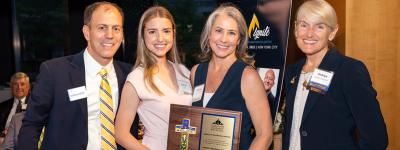 CMN's executive director, Krisanne Vaillancourt Murphy, and director of communications, Katlyn Toelle, pose for a picture with ISN staff and the award.