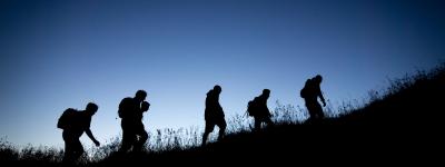 Silhouette of people climbing up a hill