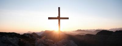 Cross on mountaintop in front of a sunrise