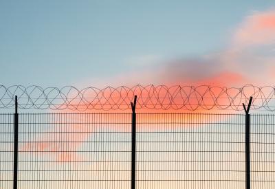 Barbed wire fence in front of blue and pink sky