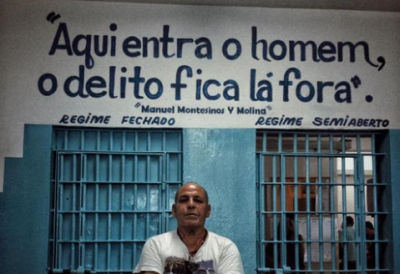 Man stands in front of doorway that reads in Spanish "the man enters, the crime stays outside."