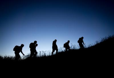 Silhouette of people climbing up a hill