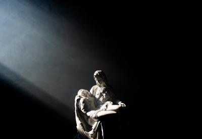 A beam of light is cast upon a statue of the Pietà